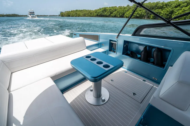 Slide: The Image of Luxurious 2018 VanDutch 30 yacht interior with white seating and blue table, cruising on a scenic waterway. - 15
