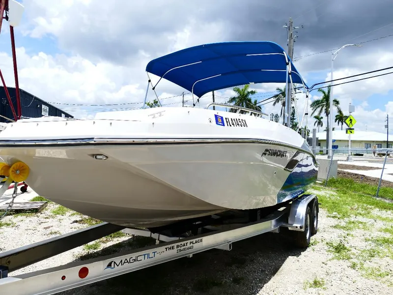 Slide: The Image of 2021 Starcraft SVX 211 OB boat on trailer with blue canopy, parked outdoors. - 2