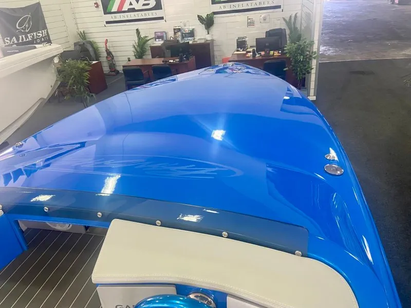Slide: The Image of 2023 Active Thunder 22 Banshee boat, sleek blue design in showroom setting. - 7