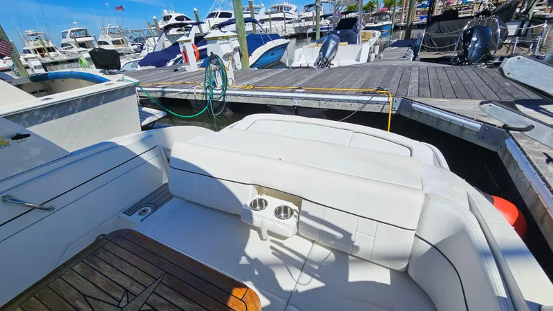 Slide: The Image of 2016 Sea Ray 230 SLX boat interior at marina, featuring white seating and wooden deck. - 18