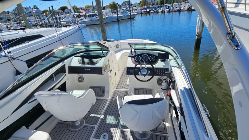 Slide: The Image of 2016 Sea Ray 230 SLX boat interior with steering wheel and seating, docked at marina. - 20