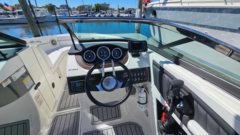 Slide: The Image of 2016 Sea Ray 230 SLX boat cockpit with steering wheel and dashboard, docked at marina. - 26