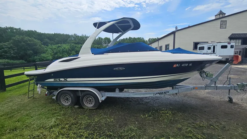 Slide: The Image of 2016 Sea Ray 230 SLX boat on trailer, parked outdoors near a building. - 3