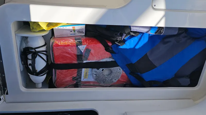 Slide: The Image of Storage compartment in a 2016 Sea Ray 230 SLX boat with life jackets and safety gear. - 33