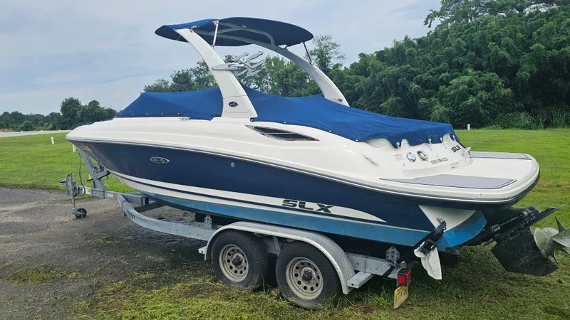 Slide: The Image of 2016 Sea Ray 230 SLX boat on trailer, covered with blue tarp, parked on grass. - 5