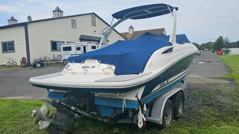 Slide: The Image of 2016 Sea Ray 230 SLX boat on trailer with blue cover, parked near building. - 6
