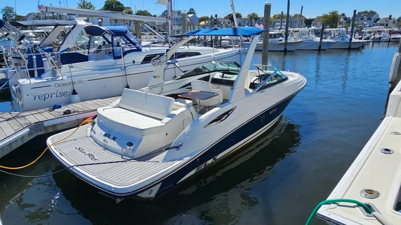 Slide: The Image of 2016 Sea Ray 230 SLX boat docked in marina, featuring sleek design and blue canopy. - 7