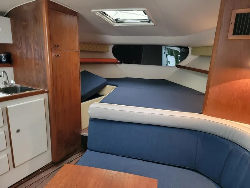 Slide: The Image of Interior of 1995 Tiara Yachts 3100 Open, featuring cozy seating and compact kitchenette. - 10