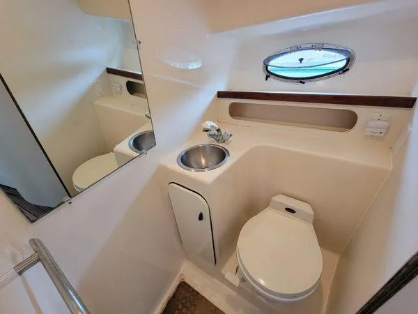 Slide: The Image of Compact yacht bathroom with sink, toilet, mirror, and porthole in 1995 Tiara Yachts 3100 Open. - 20