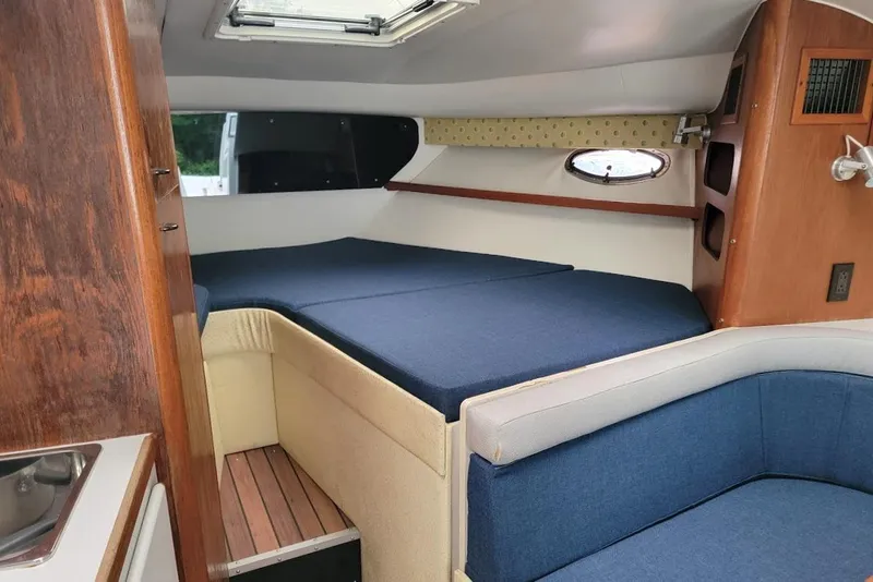 Slide: The Image of Interior of 1995 Tiara Yachts 3100 Open, featuring cozy blue seating and wood accents. - 6