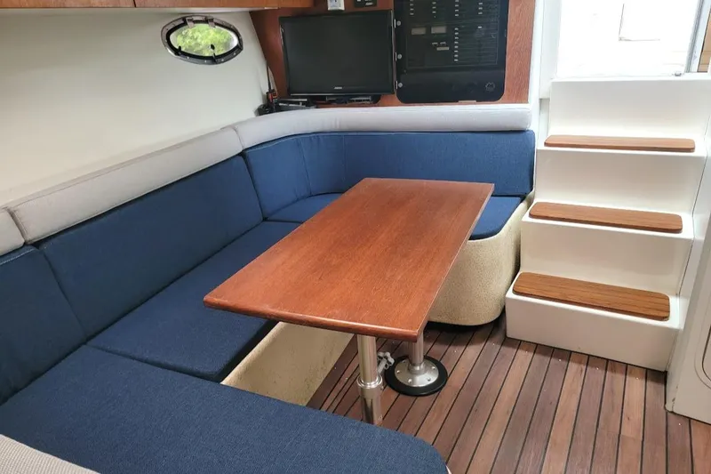 Slide: The Image of Interior of 1995 Tiara Yachts 3100 Open, featuring blue seating and wooden table. - 7