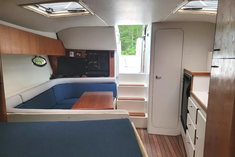 Slide: The Image of Interior of 1995 Tiara Yachts 3100 Open, featuring seating, table, and compact kitchen area. - 8