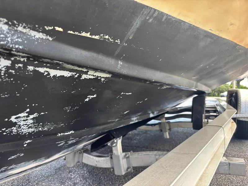 Slide: The Image of 2003 KenCraft 235 Challenger boat hull with peeling paint on a trailer. - 14