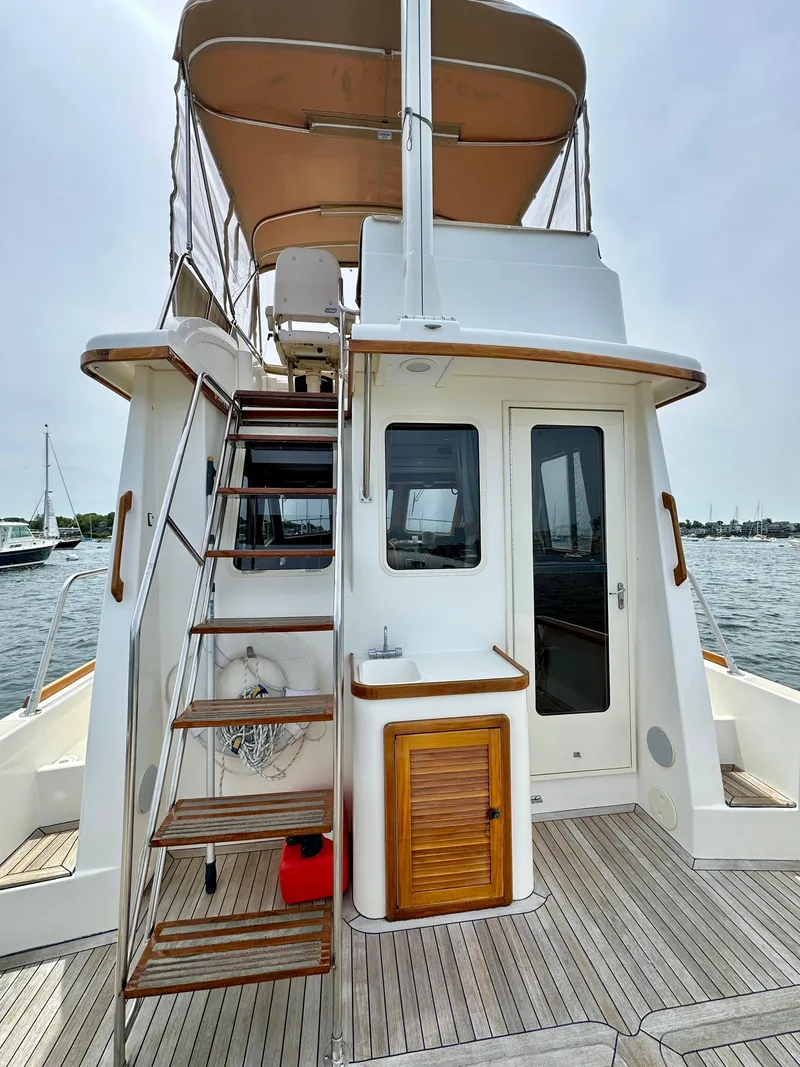 Slide: The Image of 2002 Sabreline 36 Flybridge yacht with wooden deck and stairs, docked on calm water. - 27