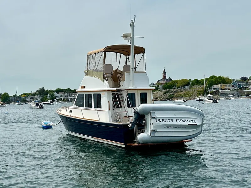 Slide: The Image of 2002 Sabreline 36 Flybridge boat named "Twenty Summers" on water near coastal town. - 5