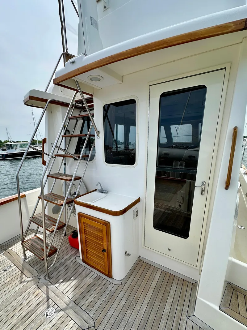 Slide: The Image of 2002 Sabreline 36 Flybridge yacht with wooden deck and ladder, docked at marina. - 6