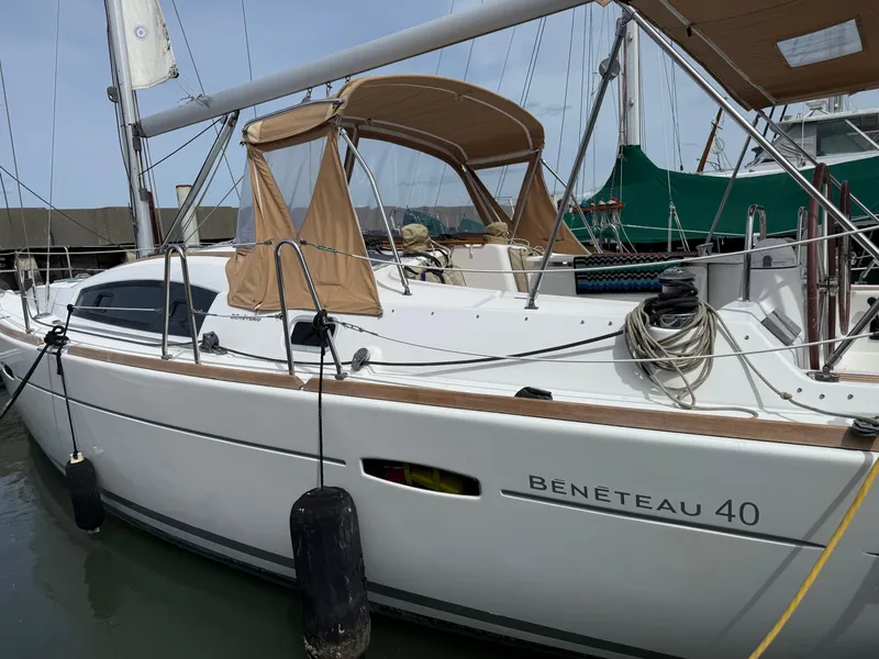 Slide: The Image of 2008 Beneteau Oceanis 40 sailboat docked, featuring beige canopy and sleek design. - 2