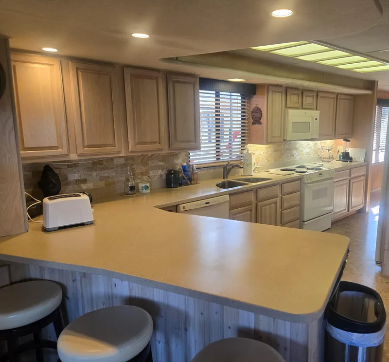 Slide: The Image of Kitchen interior of 1996 Sumerset 82'x 18' Widebody Houseboat with wooden cabinets and appliances. - 23