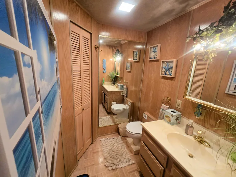 Slide: The Image of Cozy bathroom in 1996 Sumerset houseboat with wood paneling, mirror, and beach-themed decor. - 28