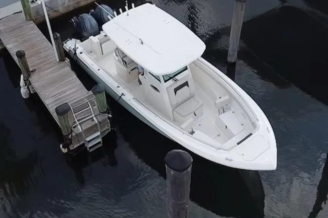 Slide: The Image of 2019 Sailfish 270 boat docked, aerial view, white hull, twin engines, calm water. - 5