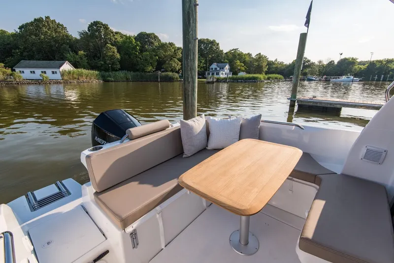 Slide: The Image of 2025 Beneteau Antares 7 boat with outdoor seating and table by a serene lake. - 6