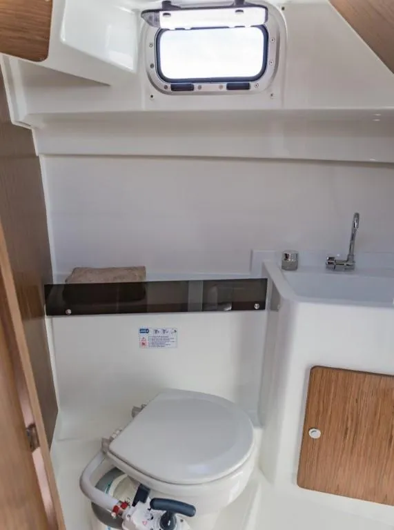 Slide: The Image of 2025 Beneteau Antares 8 boat bathroom with toilet, sink, and window. - 8