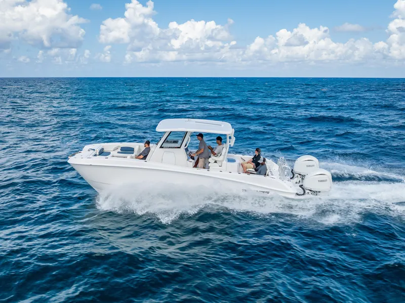 Slide: The Image of 2026 Twin Vee 260 GFX2 CC boat cruising on ocean near coastal buildings. - 11