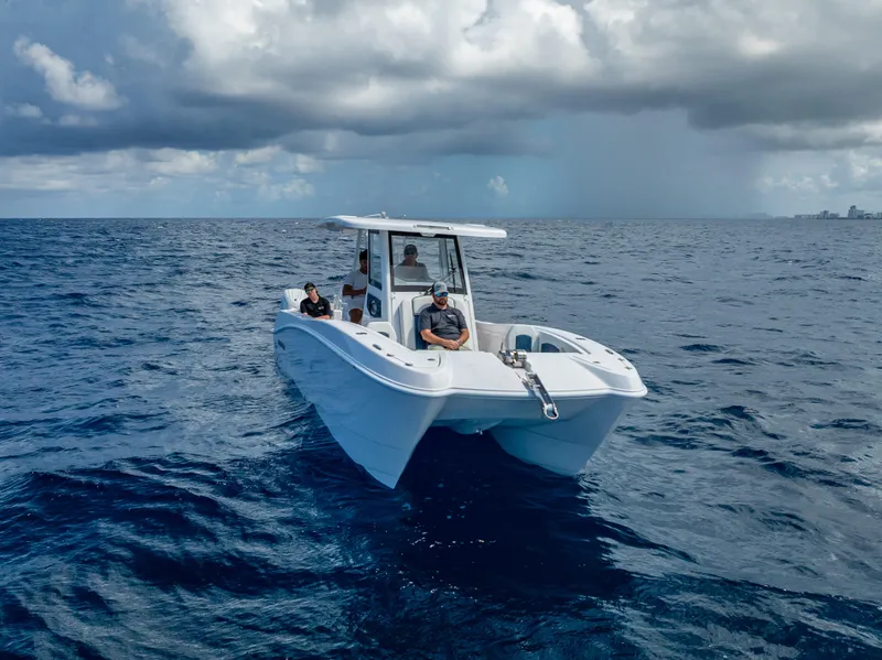 Slide: The Image of 2026 Twin Vee 260 GFX2 CC boat cruising on open ocean under cloudy sky. - 18