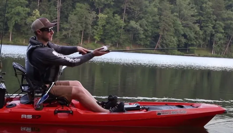 Slide: The Image of Man fishing from a red 2025 Bonafide RS117 kayak on a calm lake. - 8