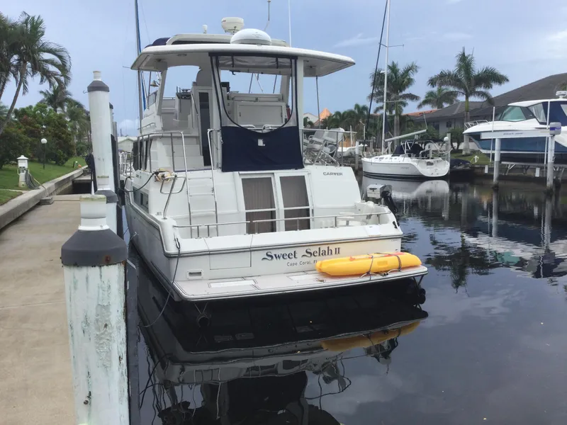 Slide: The Image of 1995 Carver 430 Cockpit Motor Yacht docked in a marina with palm trees. - 2