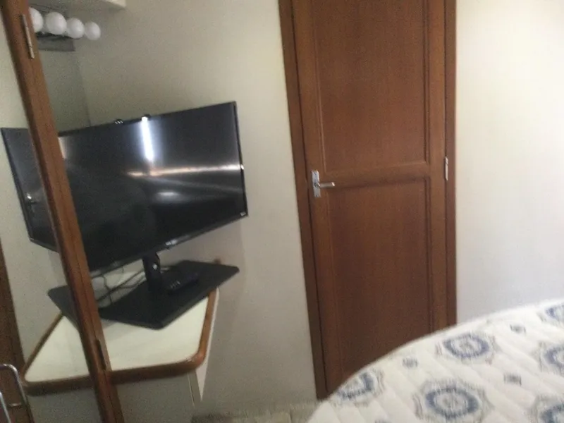 Slide: The Image of Interior of 1995 Carver 430 Yacht with TV, wooden door, and patterned bedding. - 43