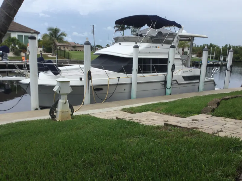 Slide: The Image of 1995 Carver 430 Cockpit Motor Yacht docked by a grassy waterfront. - 0
