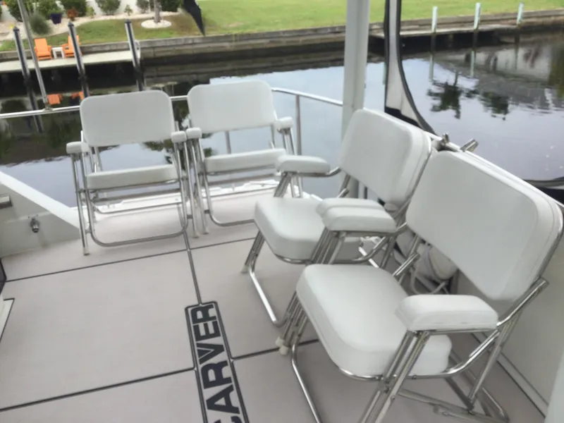 Slide: The Image of 1995 Carver 430 Cockpit Motor Yacht with white seating on deck by water. - 4