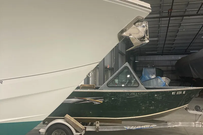 Slide: The Image of 2023 Regulator 28 Forward Seating boat in storage, alongside a smaller boat on a trailer. - 2