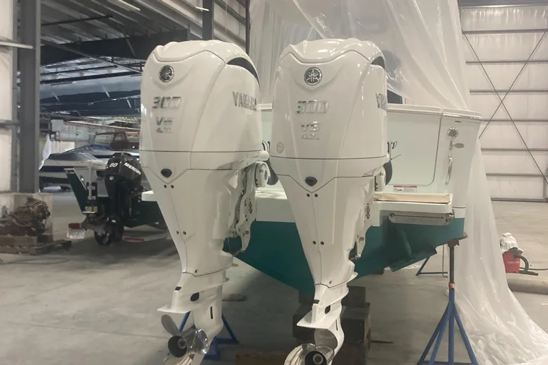 Slide: The Image of 2023 Regulator 28 Forward Seating boat with twin Yamaha 300 V6 engines in a warehouse. - 7