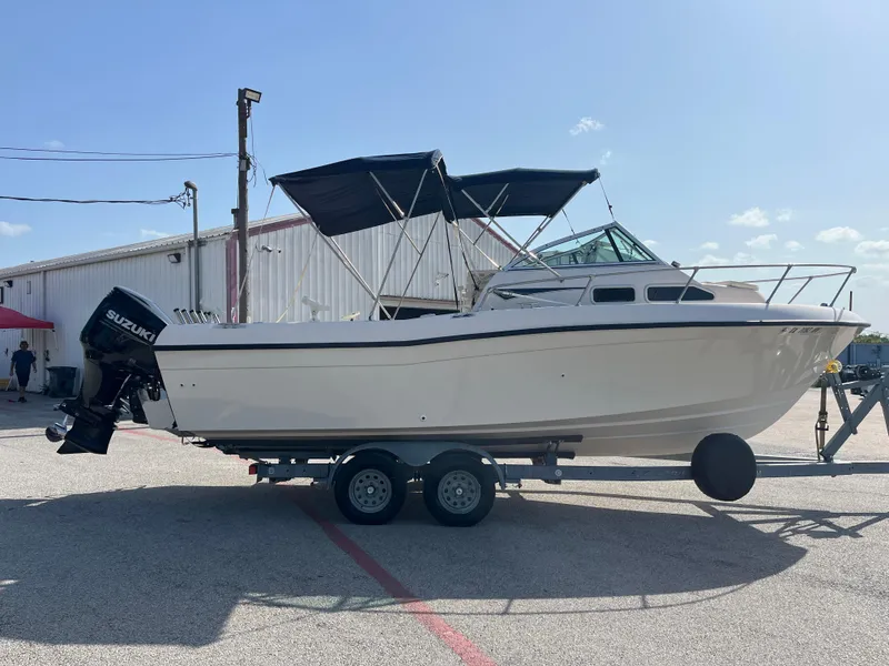 Slide: The Image of 1997 Grady-White 232 Gulfstream boat on trailer, parked outdoors under clear sky. - 5