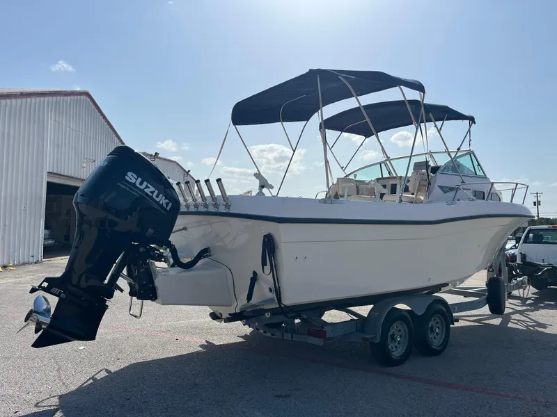 Slide: The Image of 1997 Grady-White 232 Gulfstream boat with Suzuki engine and rod holders under a clear sky. - 9