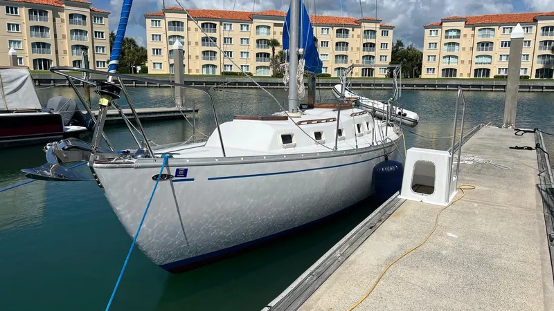 Slide: The Image of 1976 Endeavour 32' Sloop docked in marina with waterfront apartments in background. - 2