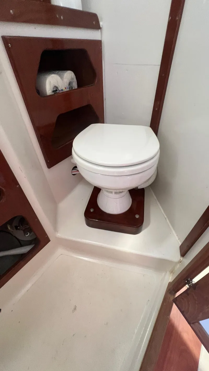 Slide: The Image of 1976 Endeavour 32' Sloop bathroom with white marine toilet and wooden accents. - 30