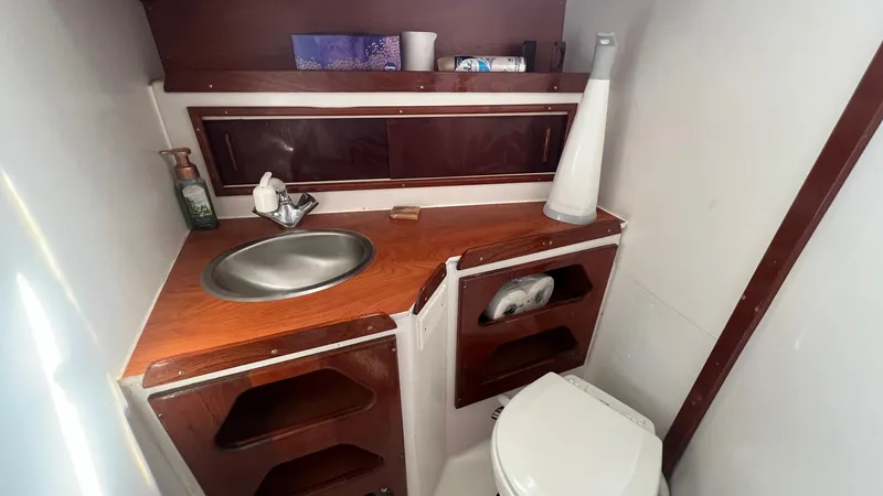 Slide: The Image of 1976 Endeavour 32' Sloop bathroom with sink, toilet, and wooden cabinetry. - 32