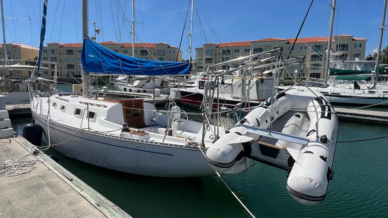 Slide: The Image of 1976 Endeavour 32' Sloop docked with inflatable dinghy, marina backdrop. - 4