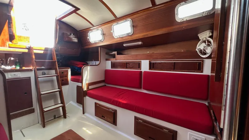 Slide: The Image of Interior of a 1976 Endeavour 32' Sloop with red cushions and wooden accents. - 42