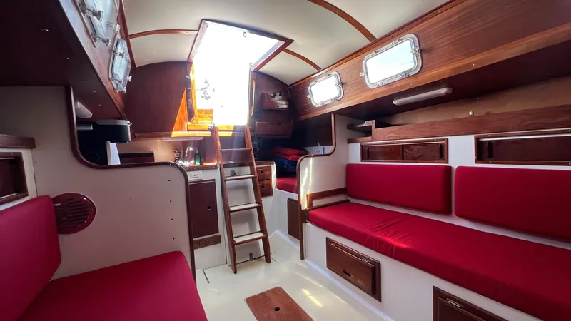 Slide: The Image of Interior of a 1976 Endeavour 32' Sloop with red seating and wooden accents. - 43