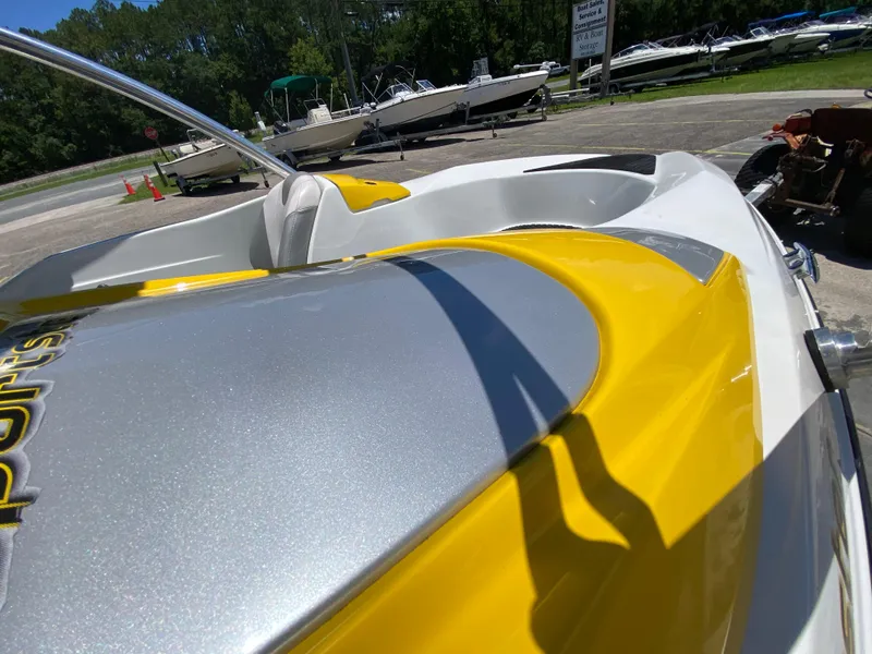 Slide: The Image of 2006 Sea-Doo Sportster boat, yellow and gray, parked outdoors with other boats in background. - 12