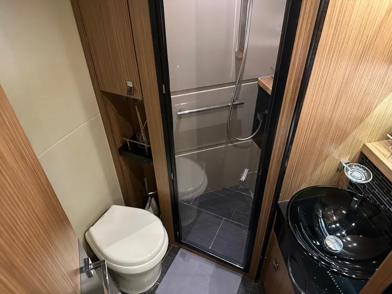 Slide: The Image of 2016 Sea Ray L590 yacht bathroom with modern fixtures and wood paneling. - 17