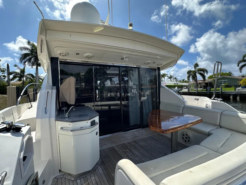 Slide: The Image of 2016 Sea Ray L590 yacht deck with seating, table, and outdoor kitchen under a sunny sky. - 30