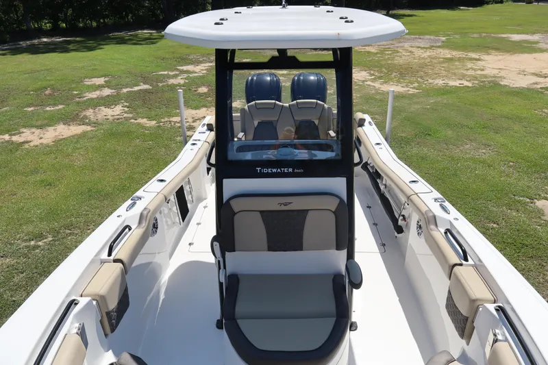 Slide: The Image of 2022 Tidewater 272 LXF boat interior with seating and console, displayed on grass. - 7