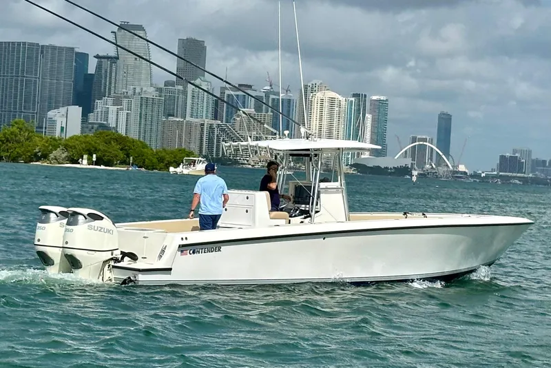 Slide: The Image of 2008 Contender 36 Open boat cruising near city skyline, featuring twin Suzuki engines. - 69