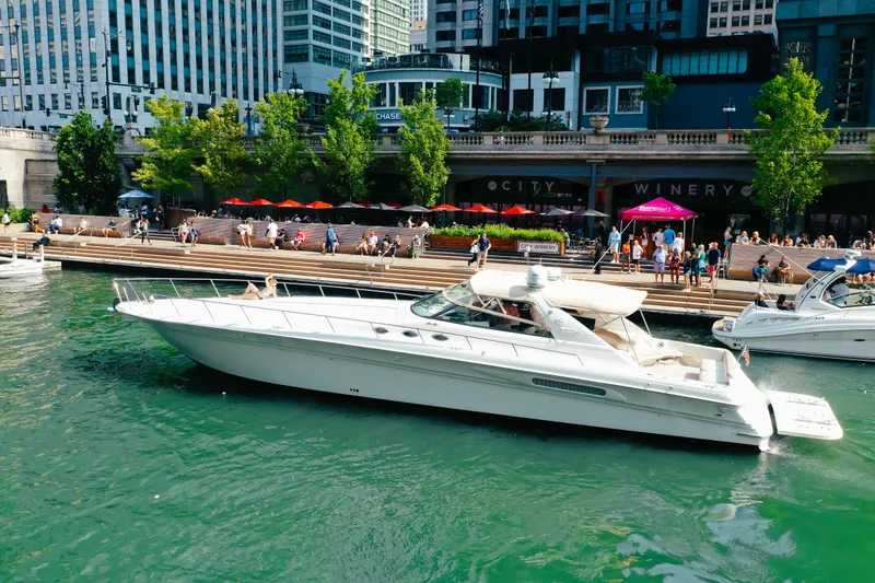 Slide: The Image of 1997 Sea Ray 630 Super Sun Sport yacht docked near a bustling waterfront cityscape. - 23
