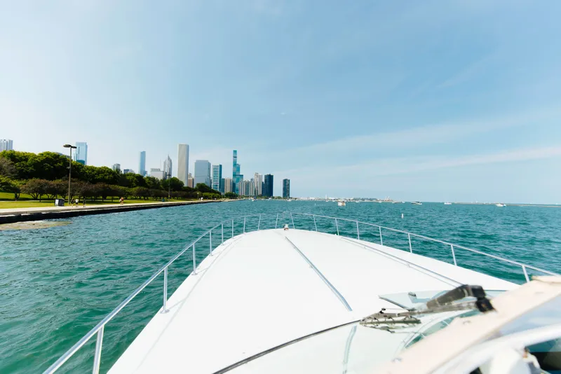 Slide: The Image of 1997 Sea Ray 630 Super Sun Sport cruising near a city skyline on a sunny day. - 35
